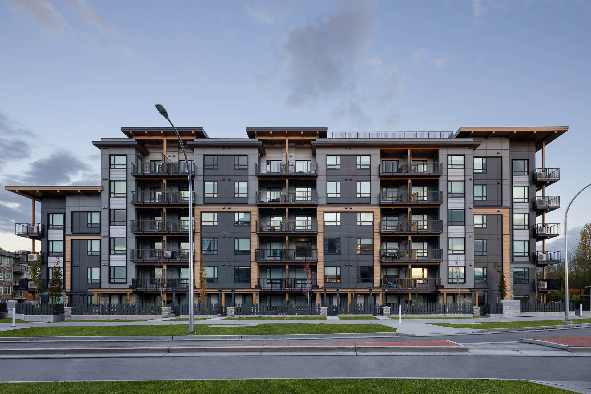 Symmetrical front exterior view of the Eden condominium building, showcasing a contemporary charcoal gray and wood-accented facade with multiple private glass balconies