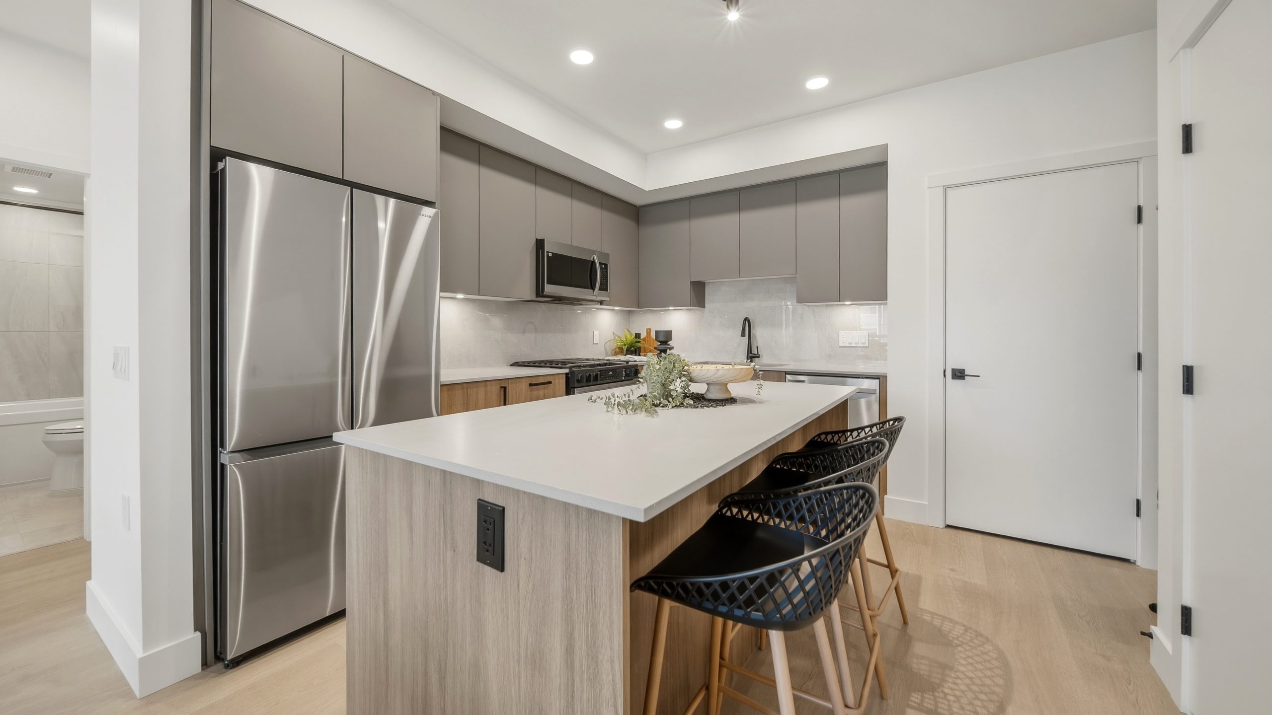 Contemporary kitchen at The Commons Langley featuring a large quartz-top island, two-tone cabinetry, stainless steel Samsung appliances, and gas range