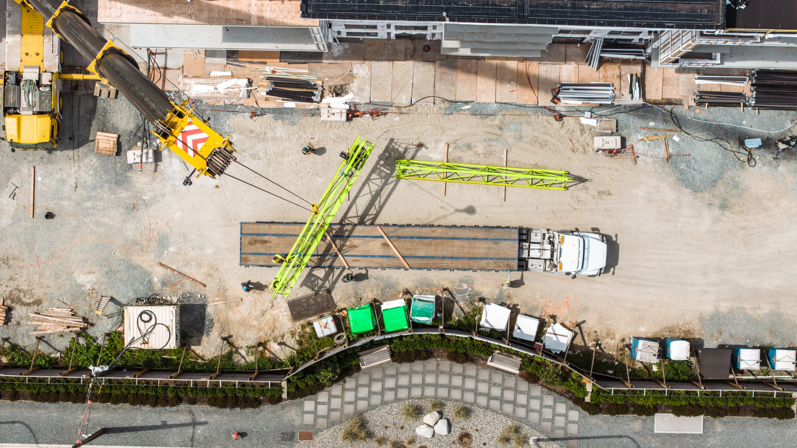 Construction crane components and flatbed delivery truck at Solana presale condos job site