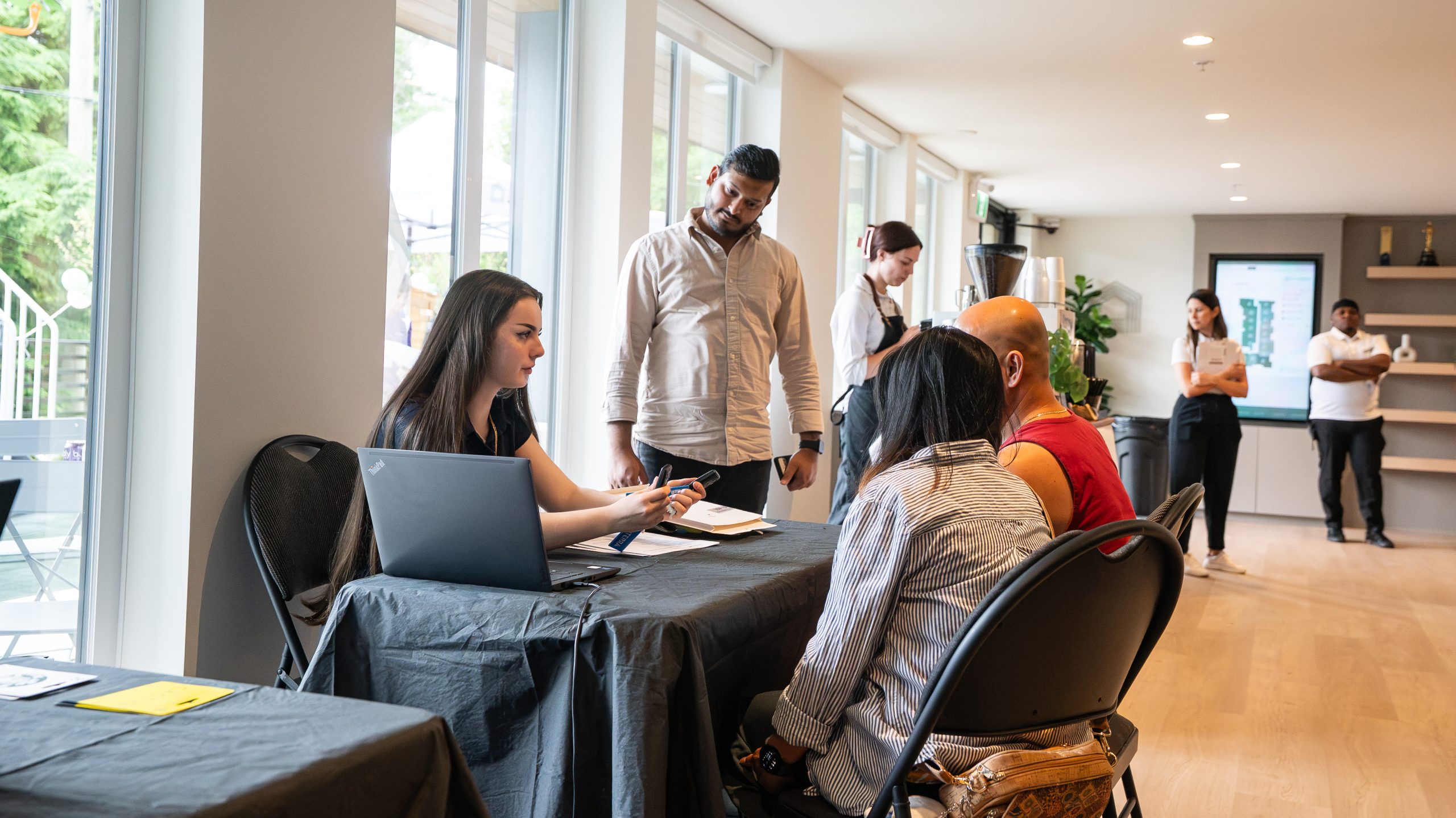 A Zenterra customer service representative assisting new homeowners at a covered check-in desk with a laptop during the City Corners move-in event
